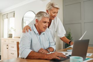 © Kay Abrahams/peopleimages.com - stock.adobe.com Foto: Zwei Pensionisten beim Esstisch mit einem Laptop